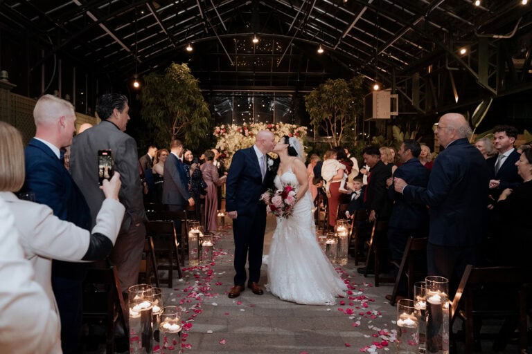 Romantic wedding ceremony at a luxurious conservatory with floral decor and candlelit ambiance.